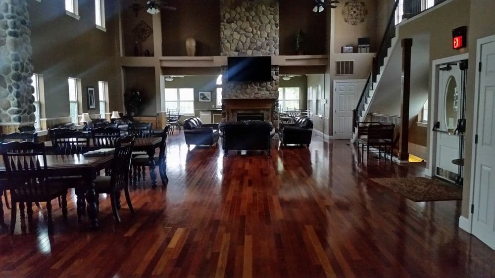 Spacious interior of a lodge with wooden floors, stone fireplace, and cozy seating areas.