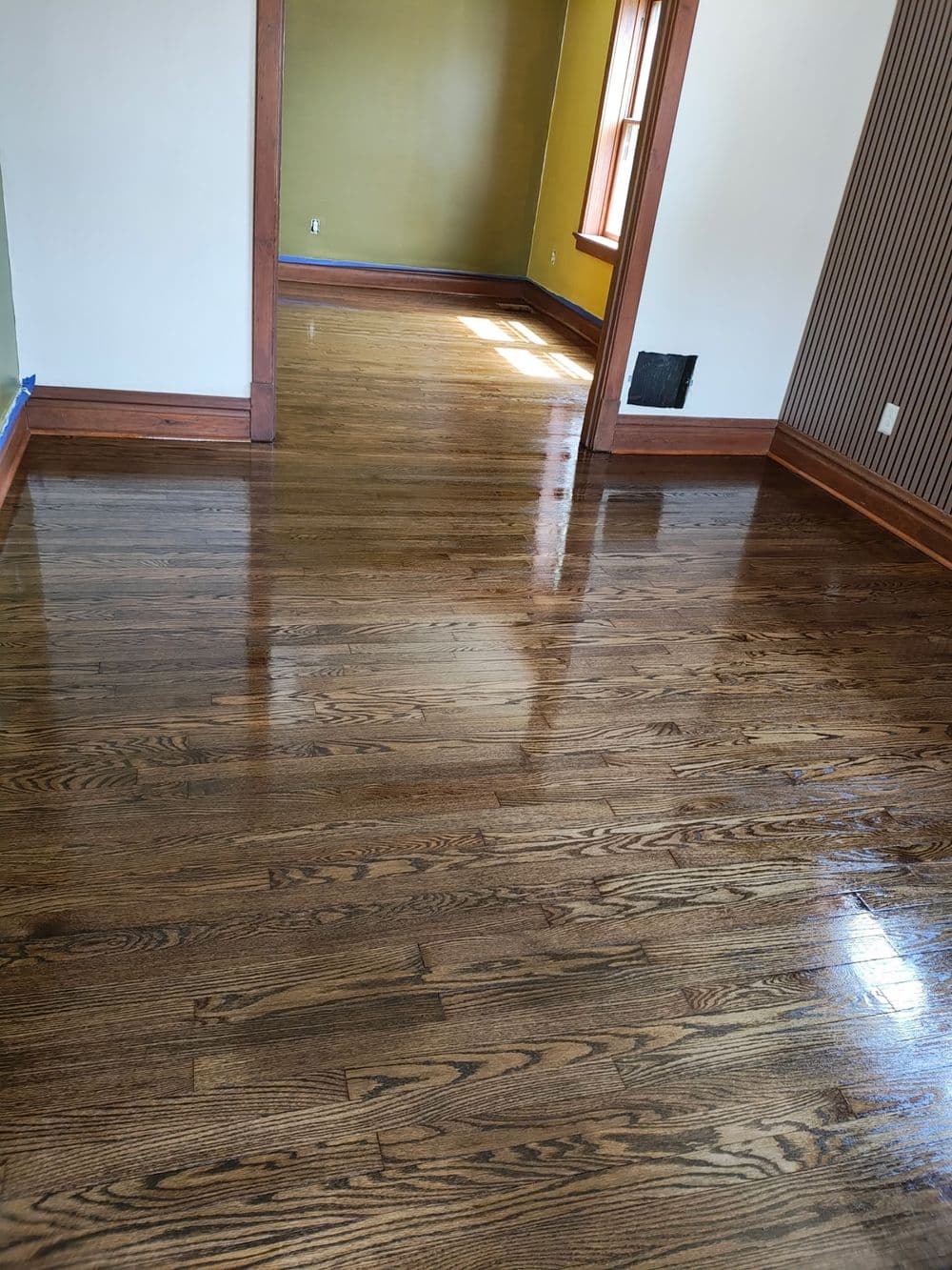 Refinished hardwood floors in a well-lit room with green and striped walls.