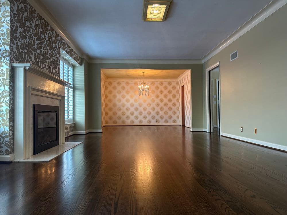 Spacious living room with hardwood floors, elegant chandelier, and stylish wallpaper accents.