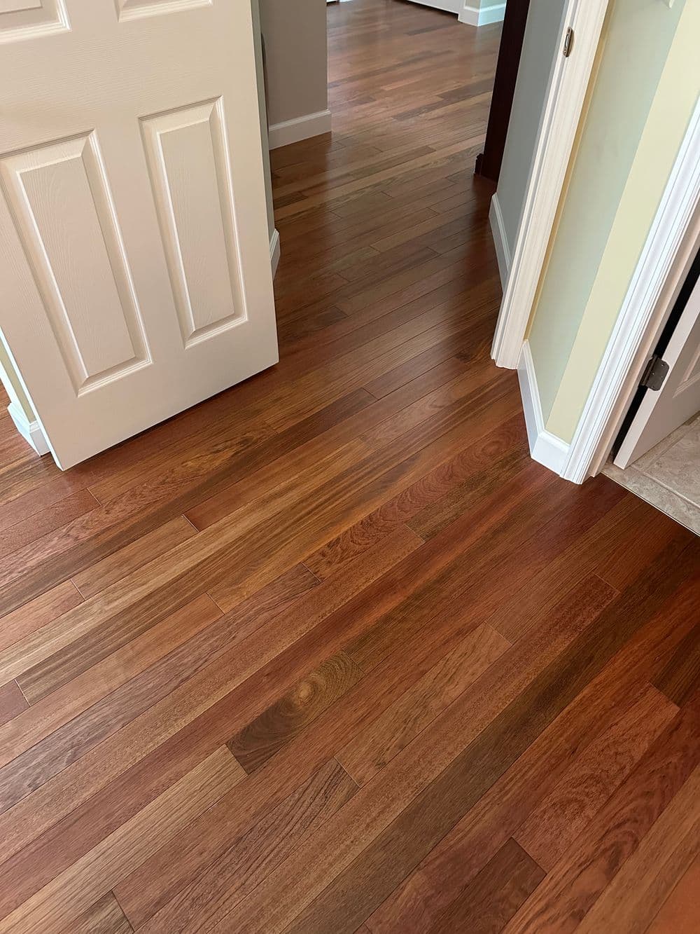 Newly installed hardwood flooring in a well-lit modern hallway with beige walls.