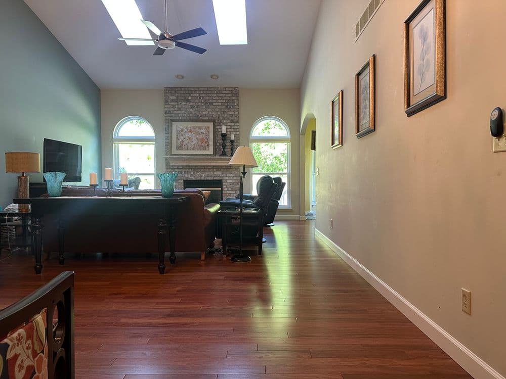 Spacious living room with a stone fireplace, hardwood floors, and elegant decor.